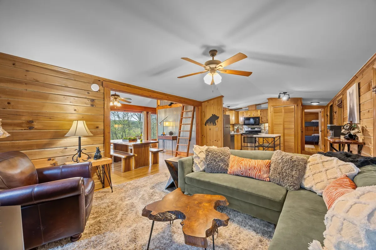 A warm, comfortable living area featuring a green sofa, wooden coffee table, cozy lighting, and wood-paneled walls—ideal for socializing, relaxing, and unwinding after a day outdoors.